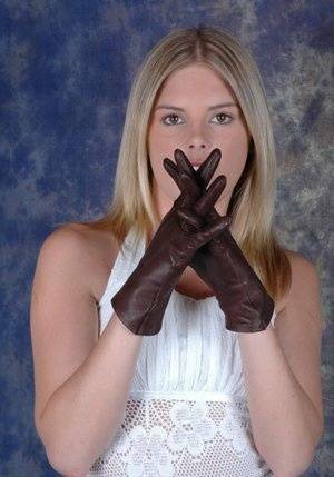 Blonde female pulls on brown leather gloves while wearing a white dress on galpictures.com