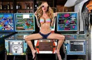 Inked chick Sarah Jessie toys her pussy atop a pinball machine while alone on galpictures.com