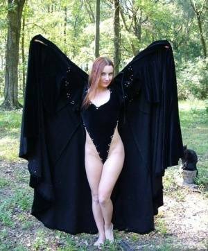 Redhead amateur Amber Lily models nude in a forest draped in a black cape on www.galpictures.com