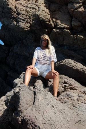 Blonde amateur Sweet Susi exposes her tits and ass on a rocks by the sea on galpictures.com