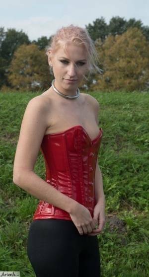 Collared girl Arienh Autumn models a red leather corset while in a field on galpictures.com