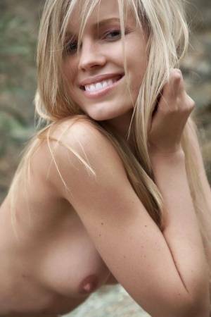 Smiling MILF Marketa shows off her nude body atop a rock outdoors on galpictures.com