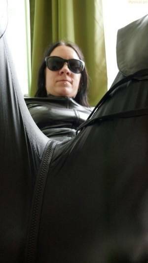 Dark haired amateur models a leather catsuit while wearing dark sunglasses on galpictures.com